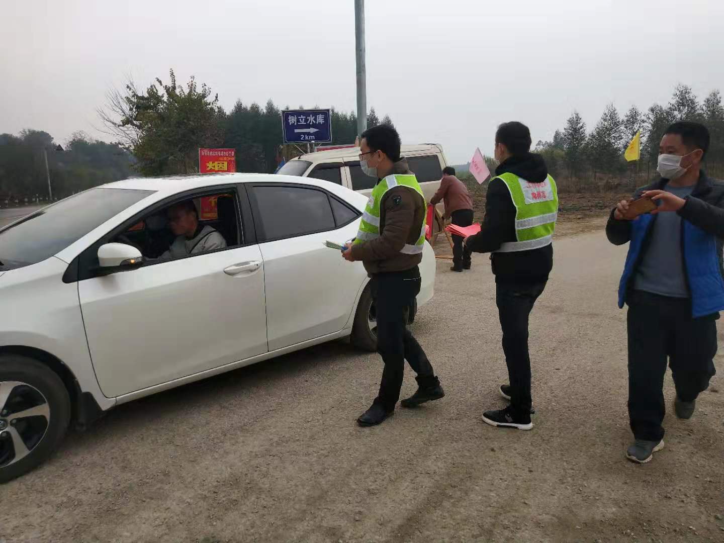 工作隊員協同村干部在路口發放宣傳材料照片.jpg